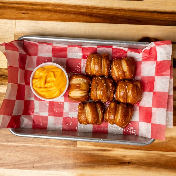 Jaxx Wing Co. pretzel bites with salt and a side of cheese dip on a metal tray.